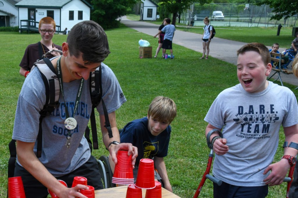 A counselor playing games with happy campers.